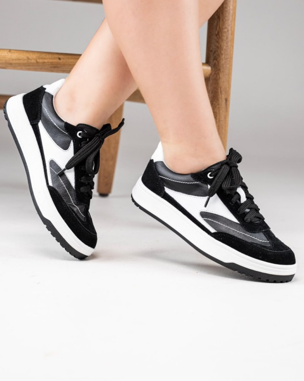 Tenis Black negros con paneles blancos y suela blanca puestos en ambos pies